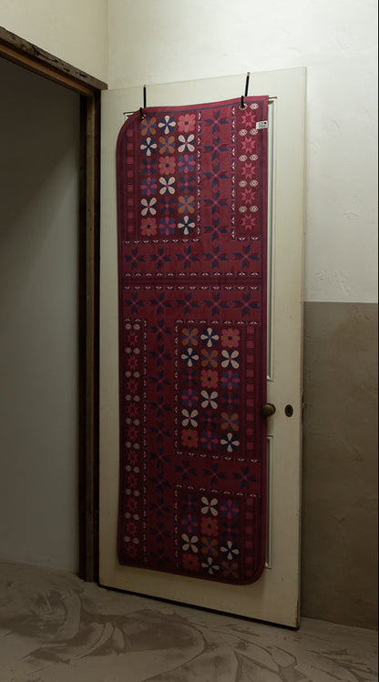 Yoga Mat with geometric pattern hanging on a door in a room.
