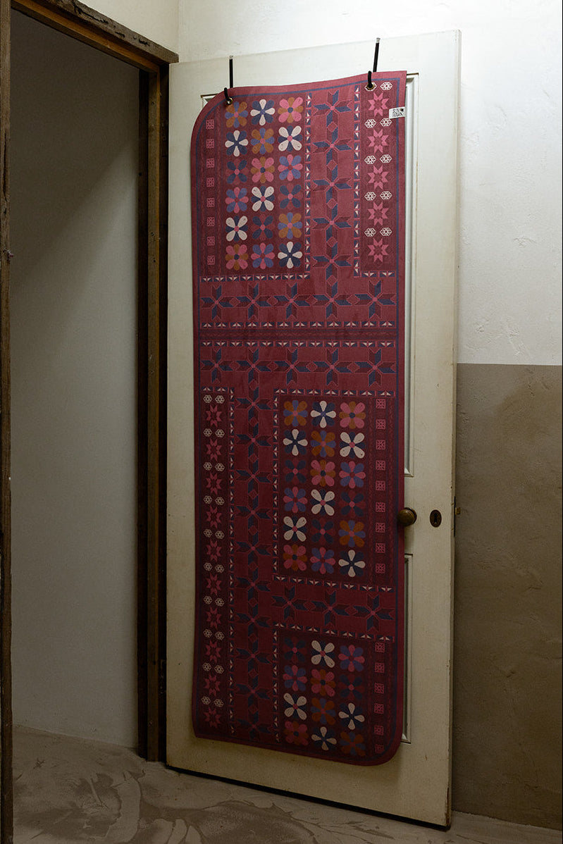 Australian designed yoga mat with floral patterns hanging on a door in a room.