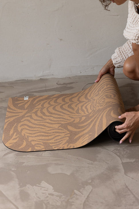 Woman unrolling a yoga mat on a concrete floor.