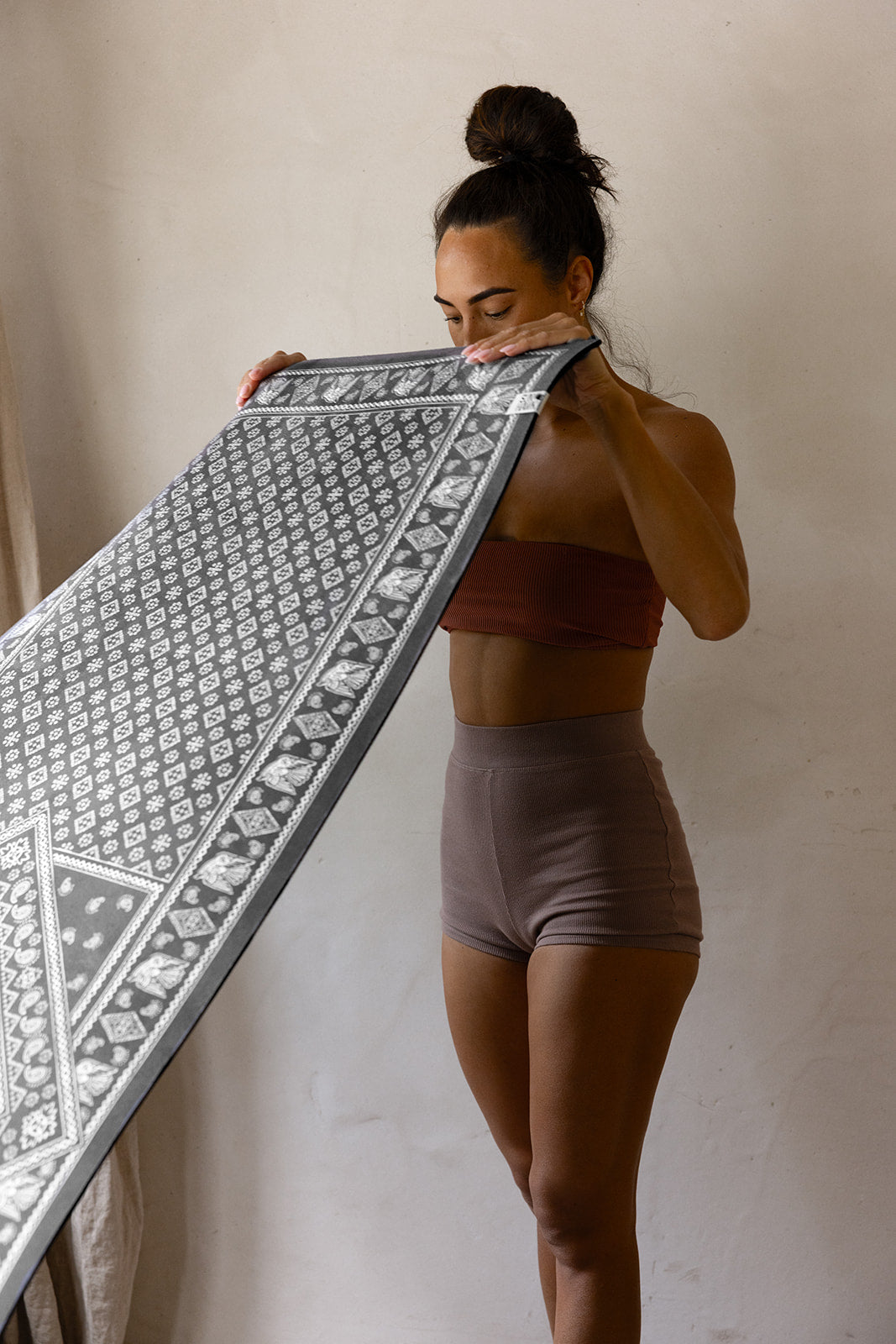 Woman holding a premium yoga and pilates mat with a geometric pattern.