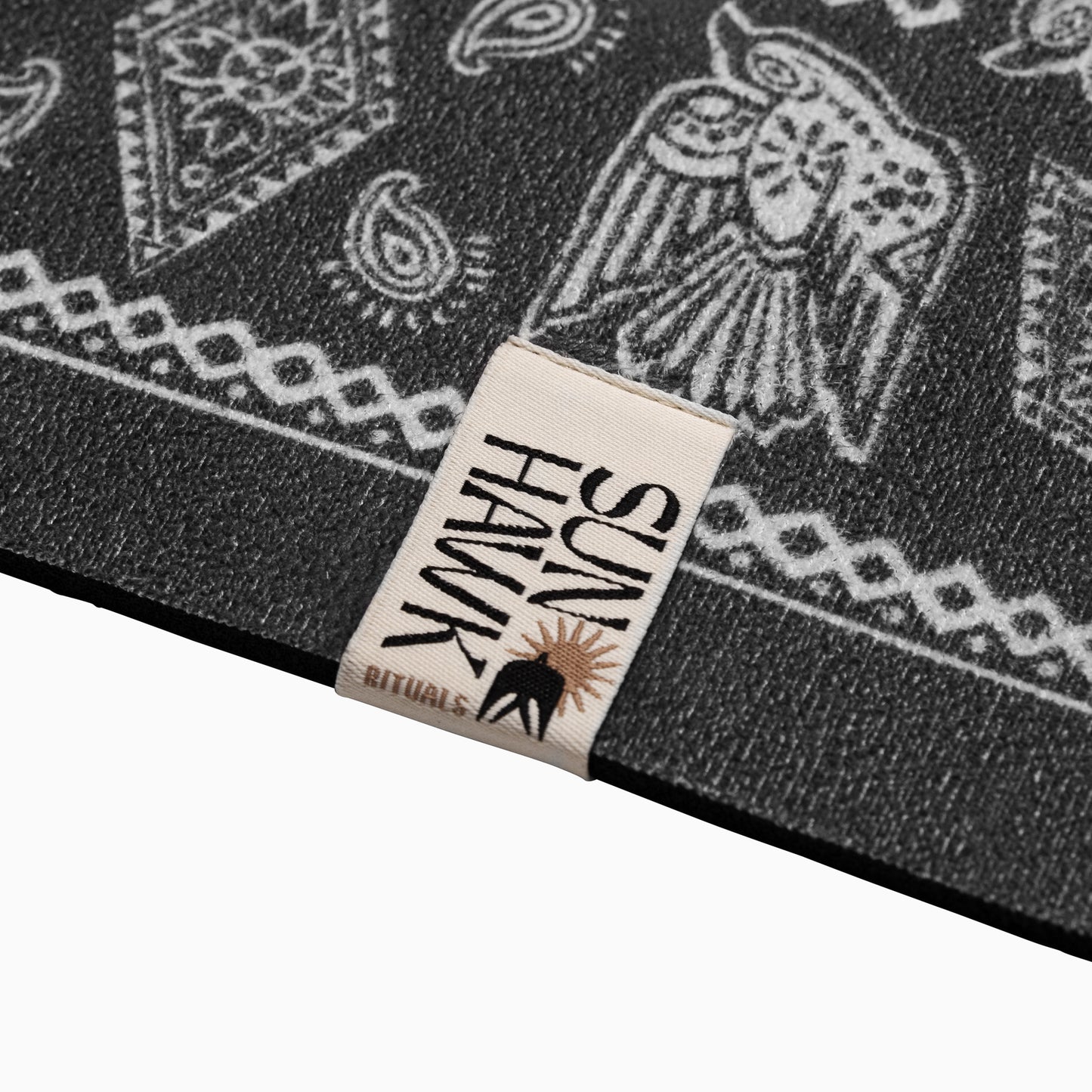 Close-up of a black and white patterned mat with a sew on label and folk hawk art print
